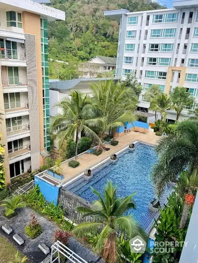 Stunning aerial view of modern apartment complex with lush greenery and inviting swimming pool.