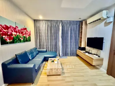 Modern living room with blue sofa, wall-mounted TV, and vibrant floral artwork.