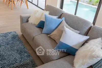 Stylish living room with cozy sofa and pool view, perfect for relaxation and entertaining.