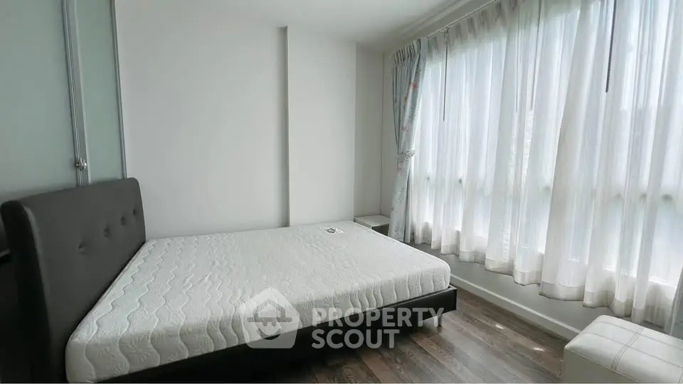 Spacious bedroom with large windows and modern decor in a bright apartment.