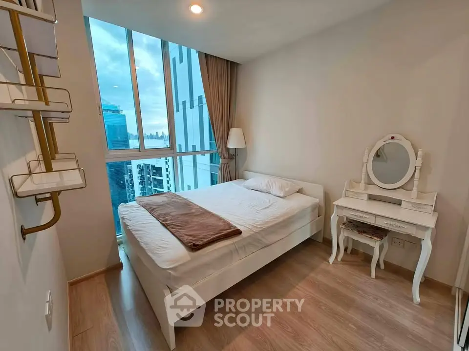 Modern bedroom with city view, featuring elegant furniture and large windows for natural light.