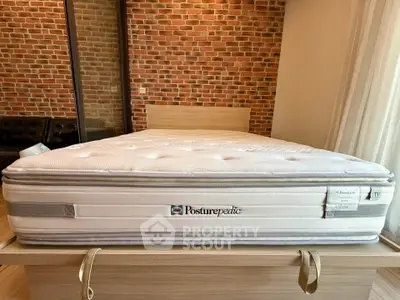 Spacious bedroom with modern brick wall and comfortable Posturepedic mattress on wooden bed frame.