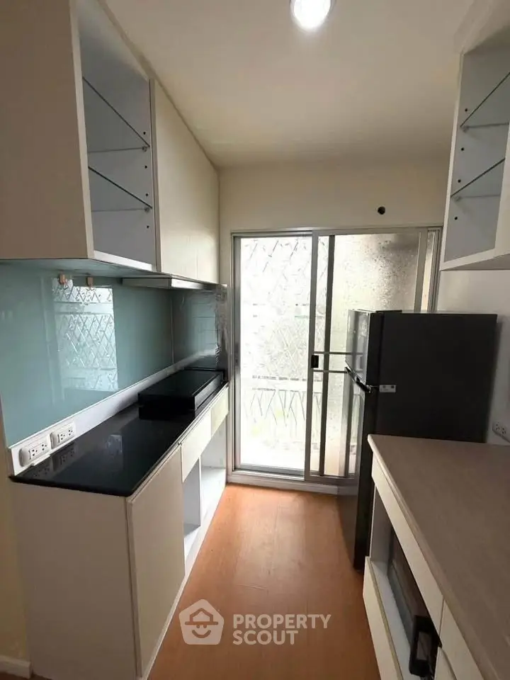Modern kitchen with sleek cabinetry and glass backsplash in a compact layout.