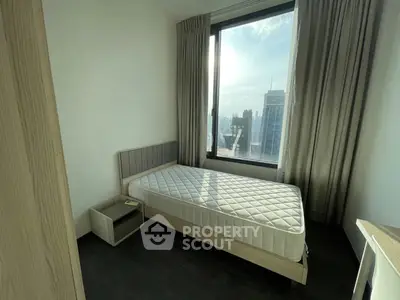Modern bedroom with large window offering stunning city views, featuring a single bed and sleek furnishings.