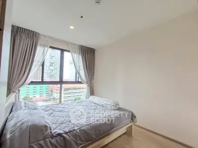 Cozy bedroom with city view, featuring a comfortable bed and large window with curtains.