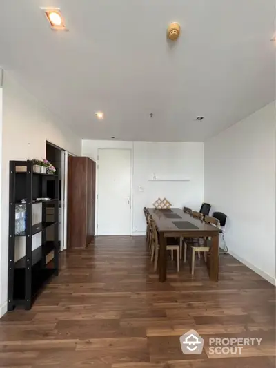 Spacious dining area with wooden flooring and modern furniture in a stylish apartment.