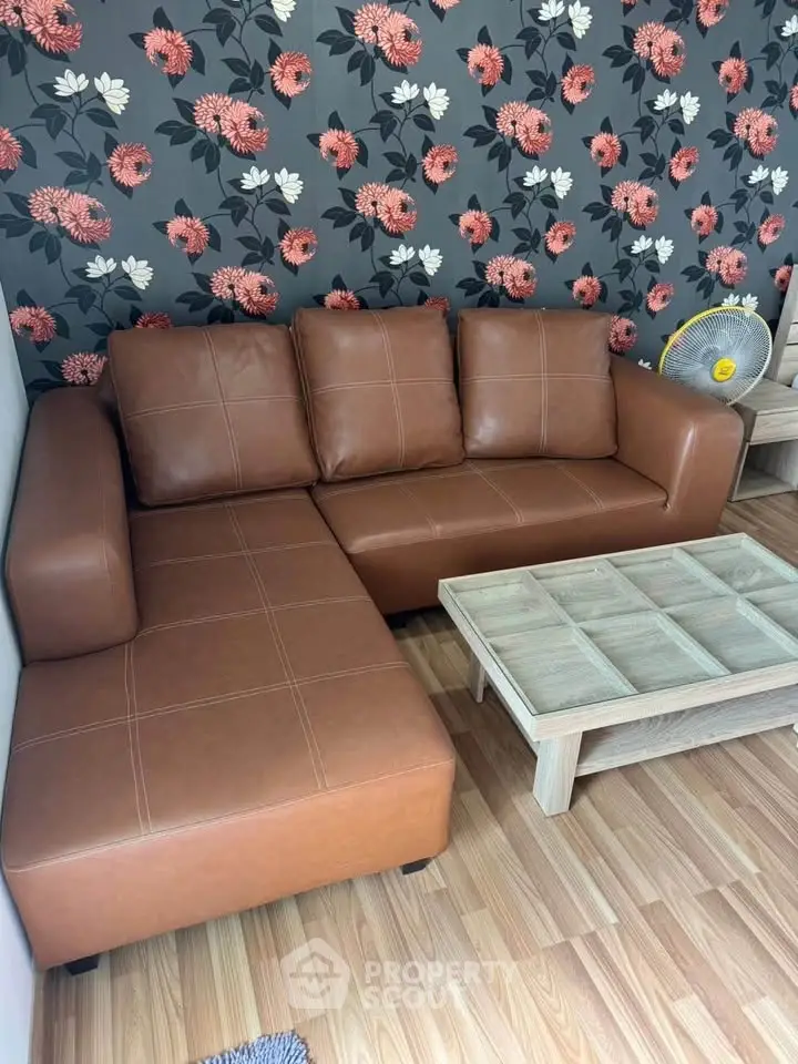Stylish living room with brown leather sofa and floral wallpaper, perfect for modern comfort.