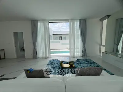Luxurious living room with pool view, elegant decor, and floor-to-ceiling windows in modern home.