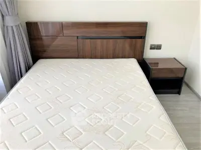 Modern bedroom with stylish wooden headboard and bedside table, featuring a comfortable mattress.
