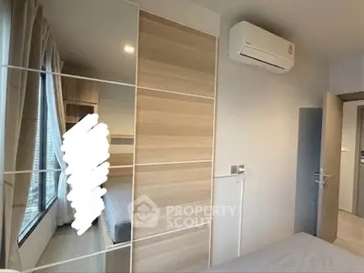 Modern bedroom with large window and air conditioning, featuring sleek wooden wardrobe design.