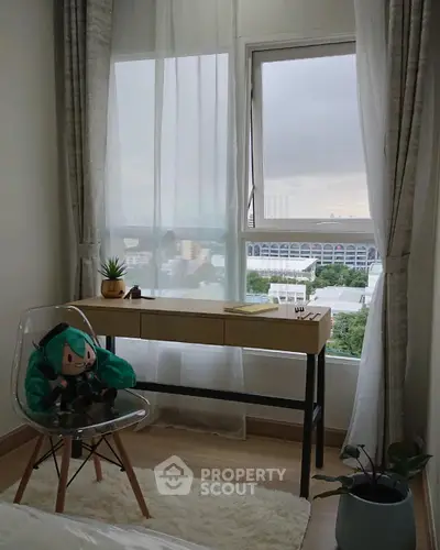 Cozy study nook with a view, featuring a modern desk and transparent chair in a bright room.