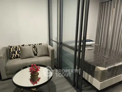 Modern studio apartment with glass partition, cozy sofa, and stylish decor.