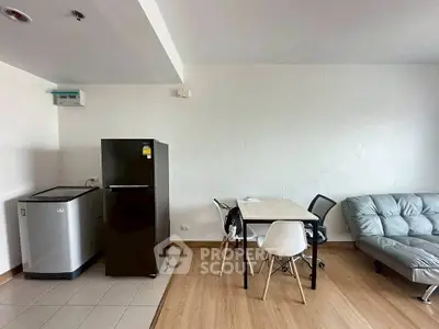Modern apartment interior with sleek kitchen and cozy living area, featuring a fridge, dining table, and stylish sofa.