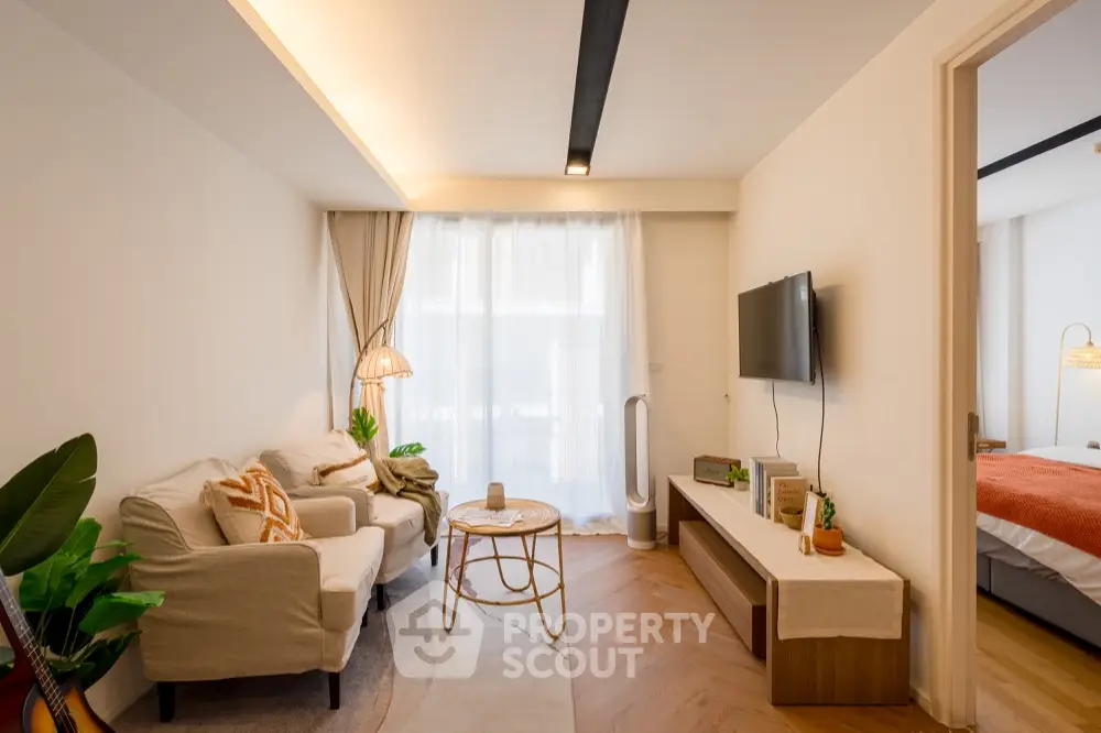 Modern living room with cozy decor and natural light, featuring a stylish TV setup and elegant furnishings.