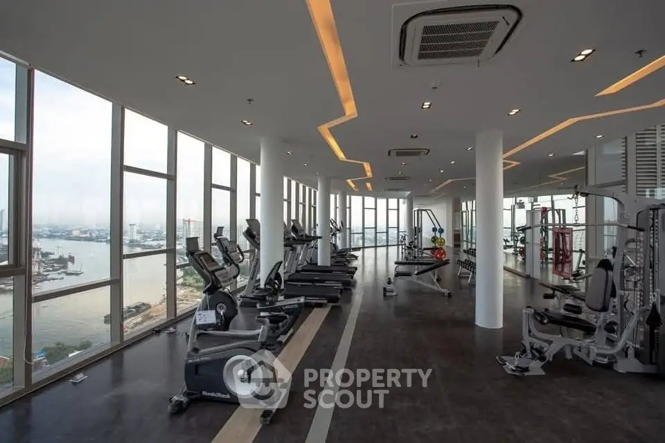 Luxurious high-rise gym with panoramic city and river views, featuring modern fitness equipment and sleek design.
