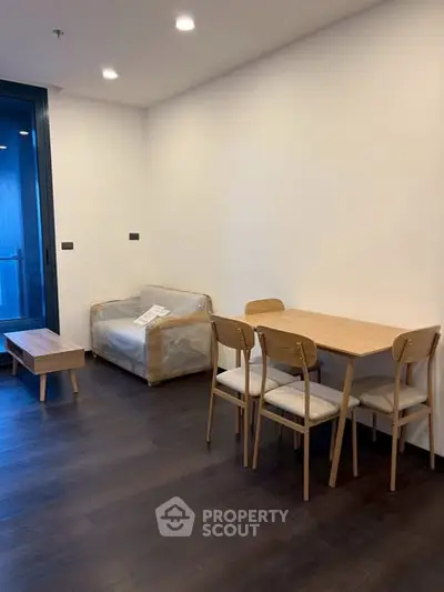 Modern living room with wooden furniture and dark flooring, featuring a cozy dining area.
