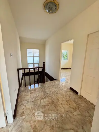 Spacious hallway with elegant marble flooring and wooden railing in modern home.