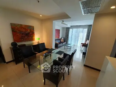 Spacious living room with modern decor and large glass table, perfect for entertaining.