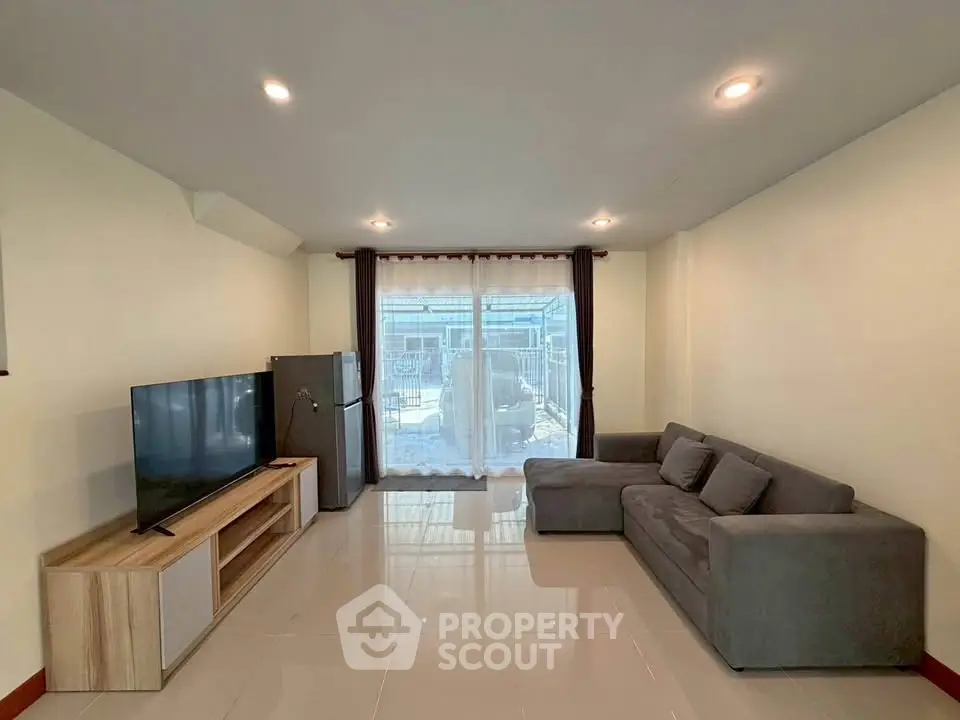 Spacious living room with modern sofa and large TV, perfect for relaxation.