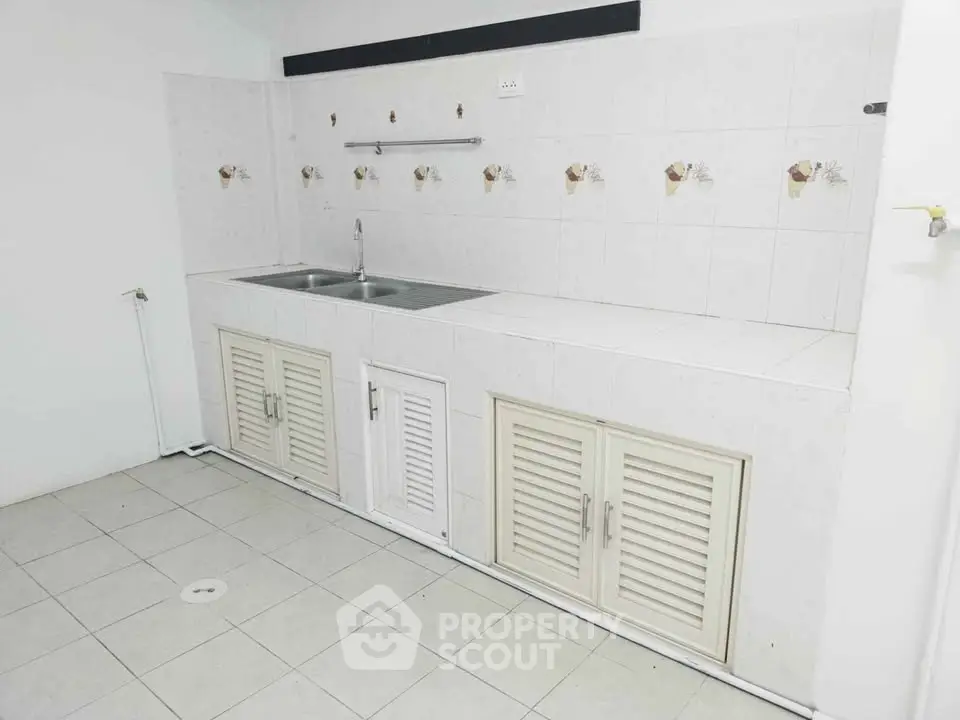 Spacious kitchen with dual sink and ample storage in a modern apartment.