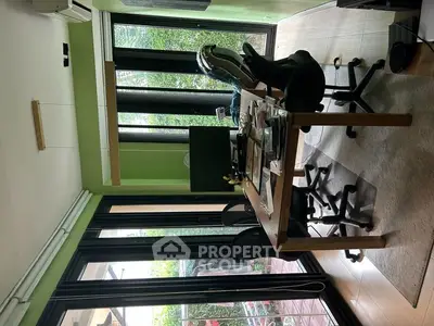 Modern study room with large windows and green walls, featuring office chairs and a wooden desk.