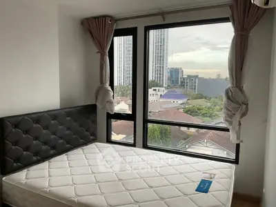 Cozy bedroom with large windows offering a stunning city view, perfect for urban living.