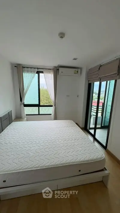 Bright bedroom with large window and balcony access, featuring a comfortable bed and modern decor.