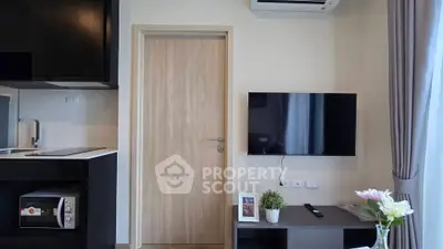 Modern living room with sleek TV setup and compact kitchen area