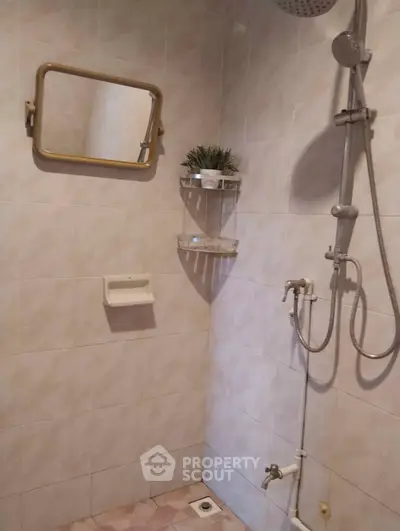 Cozy bathroom with shower and wall-mounted mirror in a tiled setting.