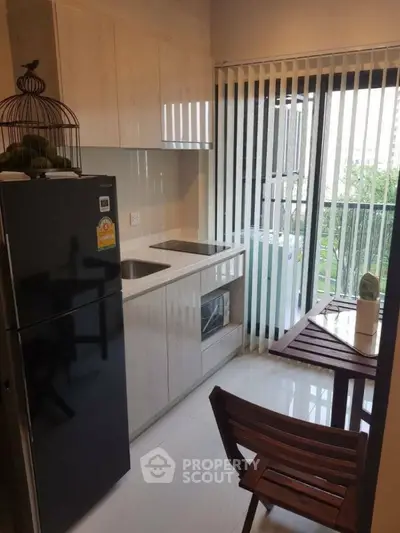 Modern compact kitchen with sleek cabinetry and large window for natural light