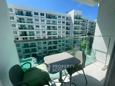 Modern balcony with glass railing overlooking pool and apartment complex, perfect for relaxation.