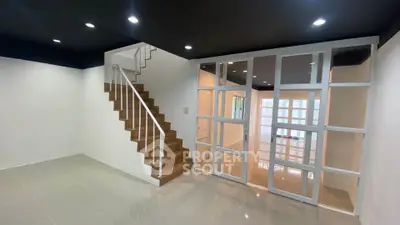 Modern interior with wooden staircase and glass partition in a spacious room.