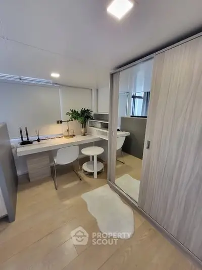 Modern study room with sleek desk, chairs, and large wardrobe in stylish apartment.