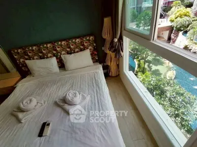 Cozy bedroom with large window overlooking lush garden and pool view.