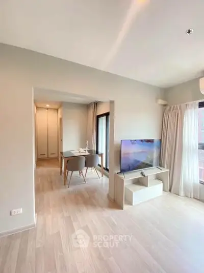 Modern living room with dining area, light wood flooring, and natural light.