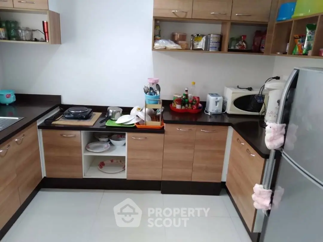 Modern kitchen with wooden cabinets and sleek appliances, featuring a gas stove and microwave.
