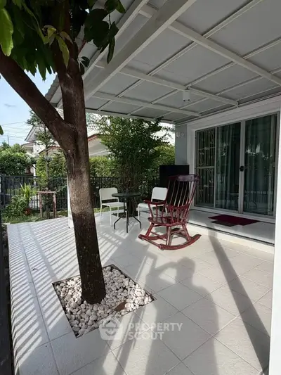 Charming patio with rocking chair and tree, perfect for relaxing outdoors.