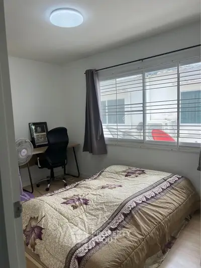 Cozy bedroom with natural light, featuring a comfortable bed and a small workspace, ideal for relaxation and productivity.