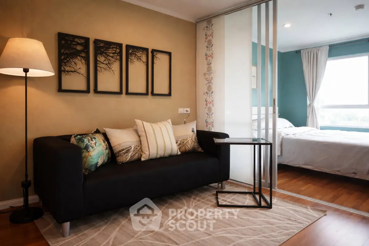 Modern living room with stylish decor and cozy ambiance, featuring a sleek black sofa and elegant wall art.