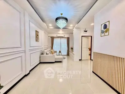 Elegant living room with chandelier and modern decor, featuring a cozy sofa and stylish wall paneling.