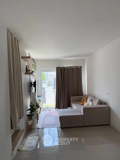 Modern living room with cozy sectional sofa and large window opening to a garden view.