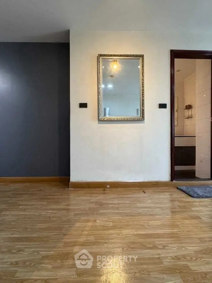 Spacious interior with wooden flooring and elegant wall mirror, ideal for modern living.