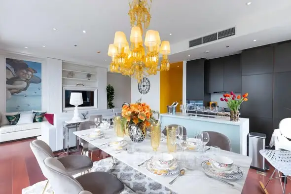 Luxurious open-plan living and dining area with elegant chandelier and modern kitchen.