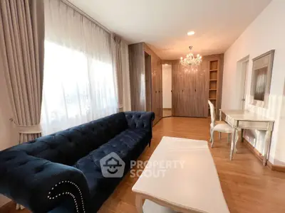 Elegant living room with plush navy sofa and chic chandelier, perfect for modern comfort.