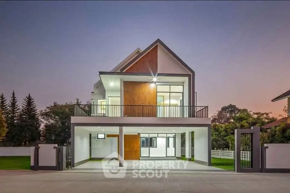 Modern two-story house with large balcony and sleek architectural design at dusk.