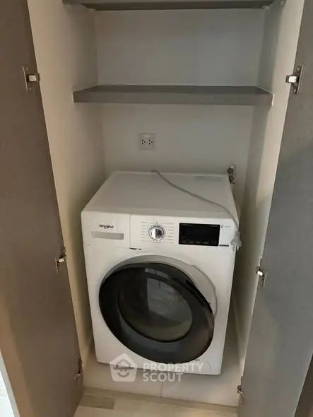 Compact laundry area with modern washing machine in a sleek cabinet.
