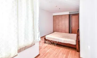 Spacious bedroom with wooden flooring and ample natural light