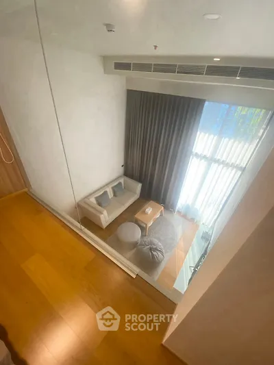 Modern living room with high ceiling and large window, featuring cozy seating and elegant curtains.