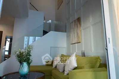 Modern living room with stylish green sofa and elegant staircase