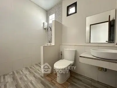 Modern bathroom with sleek design, featuring a toilet, sink, and shower area with stylish tiles.